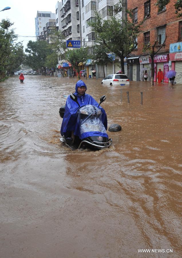 People ride in the flood water in Kunming, capital of southwest China's Yunnan Province, July 19, 2013. Kunming was hit by a heavy rainstorm from Thursday to Friday. (Xinhua/Lin Yiguang)