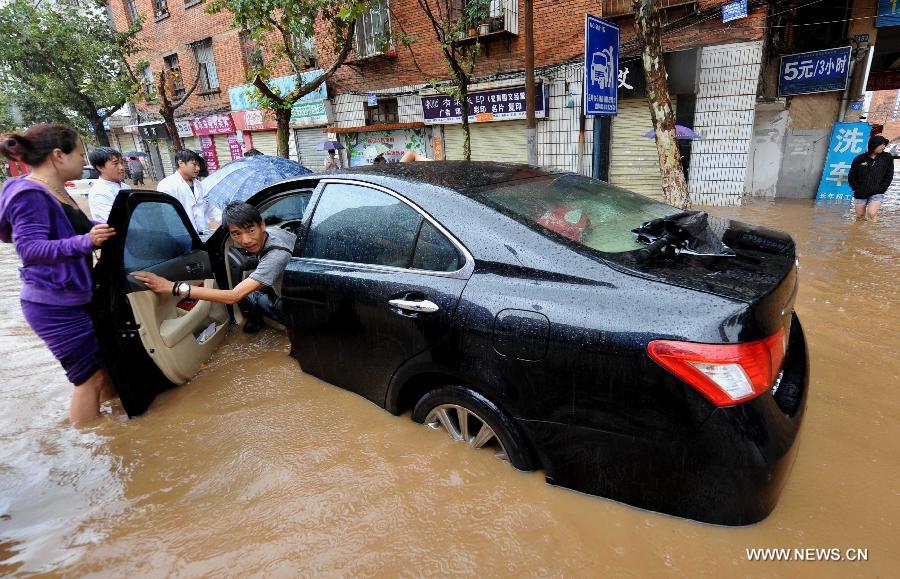 People push a submerged car in the flood water in Kunming, capital of southwest China's Yunnan Province, July 19, 2013. Kunming was hit by a heavy rainstorm from Thursday to Friday. (Xinhua/Lin Yiguang)