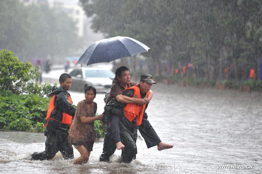 Rescuers help citizens pass the flooded Chuanjin Road in Kunming, capital of southwest China's Yunnan Province, July 19, 2013. Kunming was hit by a heavy rainstorm from Thursday to Friday. Kunming's meteorologic center on Friday issued a blue alert for rainstorm. (Xinhua/Hao Yaxin)