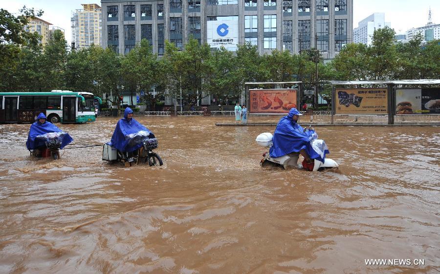 People drive on the flooded Jinbi Road in Kunming, capital of southwest China's Yunnan Province, July 19, 2013. Kunming was hit by a heavy rainstorm from Thursday to Friday. Kunming's meteorologic center on Friday issued a blue alert for rainstorm. (Xinhua/Lin Yiguang)
