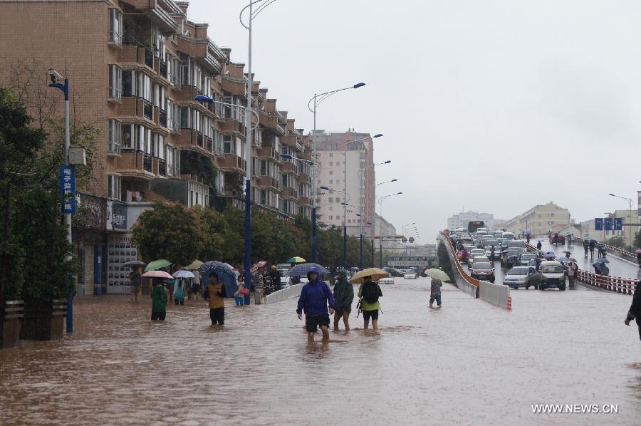 People walk on a flooded road in Kunming, capital of southwest China's Yunnan Province, July 19, 2013. Kunming was hit by a heavy rainstorm from Thursday to Friday. Kunming's meteorologic center on Friday issued a blue alert for rainstorm. (Xinhua/Liu Kelin)