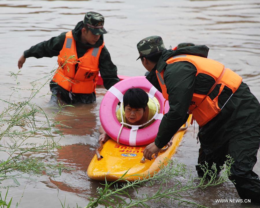 Rescuers evacute a local from the waterlogged Houjing Village at Haicang District in Xiamen, southeast China's Fujian Province, July 19, 2013. Tropical storm Cimaron made landfall in the province Thursday night, bringing rainstorms to Xiamen. Over 40 villagers were evacuated after the low-lying village was flooded. (Xinhua) 