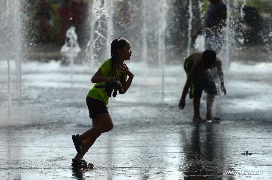 A child plays in a water fountain during a heatwave in New York of the United States, July 18, 2013. (Xinhua/Wang Lei) 