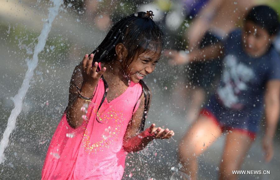 A child plays in a water fountain during a heatwave in New York of the United States, July 18, 2013.(Xinhua/Wang Lei) 