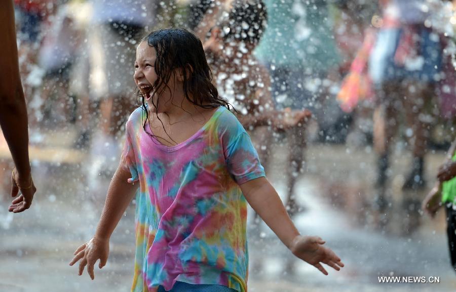 A child plays in a water fountain during a heatwave in New York of the United States, July 18, 2013. (Xinhua/Wang Lei) 