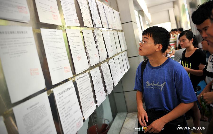Job hunters take a look at the job information during a job fair held in Haikou, capital of south China's Hainan Province, July 19, 2013. Over 6,000 job vacancies from 200 companies were provided at the job fair, attracting more than 8,000 people.(Xinhua/Guo Cheng)
