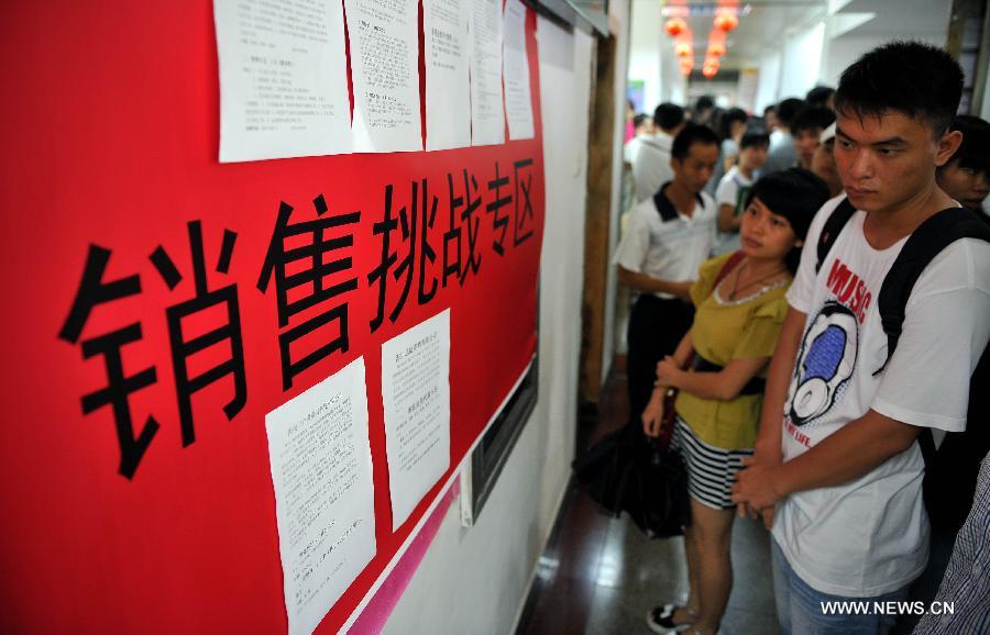 Job hunters take a look at the job information during a job fair held in Haikou, capital of south China's Hainan Province, July 19, 2013. Over 6,000 job vacancies from 200 companies were provided at the job fair, attracting more than 8,000 people.(Xinhua/Guo Cheng)