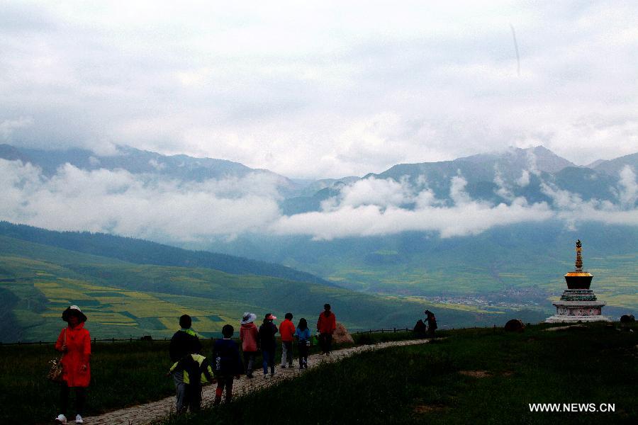 Tourists watch the snow mountain and clouds at Zhuo'er Mountain in Qilian County, northwest China's Qinghai Province, July 16, 2013. The tourist attraction witnessed a travel peak in July with its snow mountains and blossoming rape flowers. (Xinhua/Yang Shoude)
