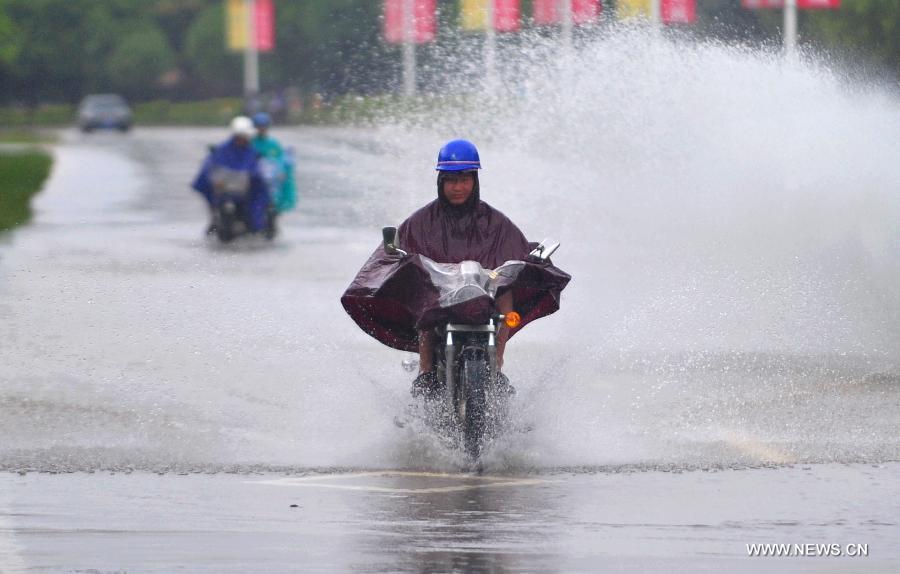 A local resident rides on a street with serious water accumulation in Longhai of Zhangzhou City, southeast China's Fujian Province, July 19, 2013. Tropical storm Cimaron made its landfall in Fujian Thursday evening, bringing heavy rain and strong gales to southern part of the province. Xiamen, Zhangzhou, Quanzhou and Putian were severely affected by the storm, with the rainfall in some regions like Longhai reaching 520 millimeters on Friday. About 123,000 residents were afflicted by the storm and no casualties have been reported yet. (Xinhua/Wei Peiquan) 
