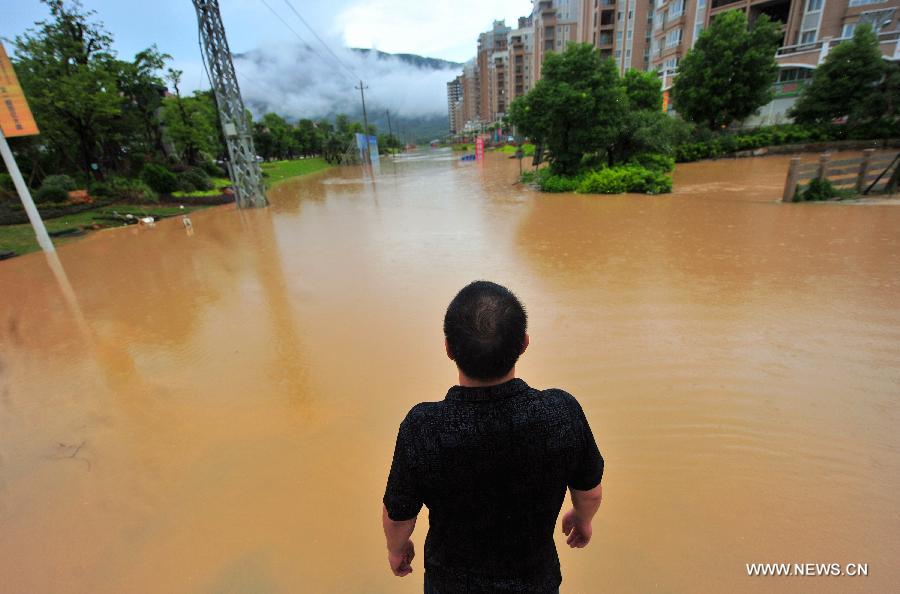 A man looks at a flooded residential community in Gangwei Township in Longhai of Zhangzhou City, southeast China's Fujian Province, July 19, 2013. Tropical storm Cimaron made its landfall in Fujian Thursday evening, bringing heavy rain and strong gales to southern part of the province. Xiamen, Zhangzhou, Quanzhou and Putian were severely affected by the storm, with the rainfall in some regions like Longhai reaching 520 millimeters on Friday. About 123,000 residents were afflicted by the storm and no casualties have been reported yet. (Xinhua/Wei Peiquan) 