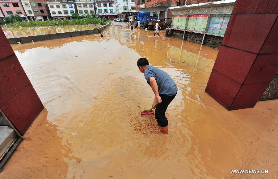 An entrance guard clears mud at the gate of government of Gangwei Township in Longhai of Zhangzhou City, southeast China's Fujian Province, July 19, 2013. Tropical storm Cimaron made its landfall in Fujian Thursday evening, bringing heavy rain and strong gales to southern part of the province. Xiamen, Zhangzhou, Quanzhou and Putian were severely affected by the storm, with the rainfall in some regions like Longhai reaching 520 millimeters on Friday. About 123,000 residents were afflicted by the storm and no casualties have been reported yet. (Xinhua/Wei Peiquan)