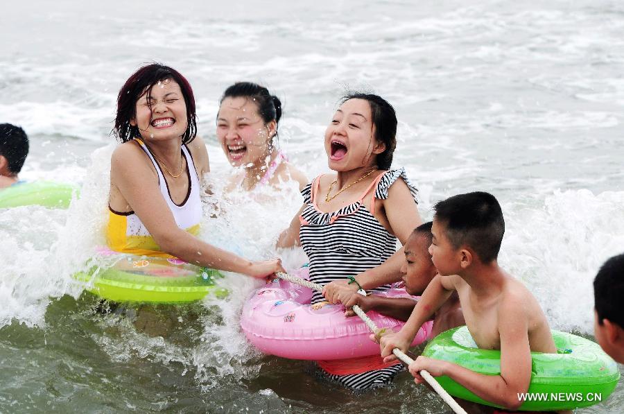 Tourists play with water at the Wanpingkou bathing beach in Rizhao, east China's Shandong Province, July 19, 2013. A large amount of tourists come here to enjoy the coolness brought by sea. (Xinhua/Yu Fangping) 