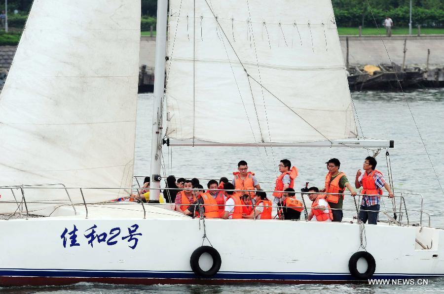 Tourists experience sailing boat at the Wanpingkou bathing beach in Rizhao, east China's Shandong Province, July 19, 2013. A large amount of tourists come here to enjoy the coolness brought by sea. (Xinhua/Yu Fangping) 