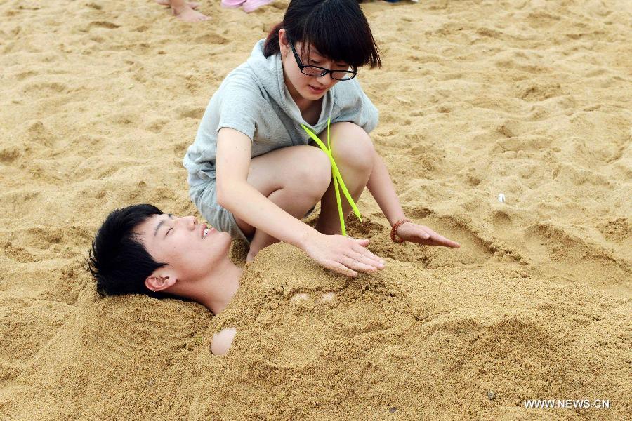 Tourists enjoy sand bath at the Wanpingkou bathing beach in Rizhao, east China's Shandong Province, July 19, 2013. A large amount of tourists come here to enjoy the coolness brought by sea. (Xinhua/Yu Fangping) 