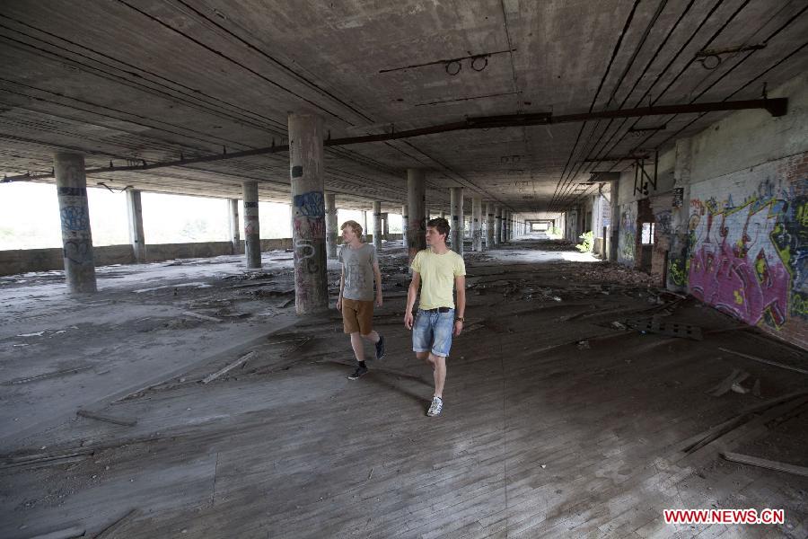 Two Belgian tourists explore the Packard Plant, an abandoned auto factory, in Detroit, midwest city of the United States, July 19, 2013. U.S. city Detroit filed for bankruptcy Thursday, making it the largest-ever municipal bankruptcy in U.S. history, local media reported. (Xinhua/Marcus DiPaola)