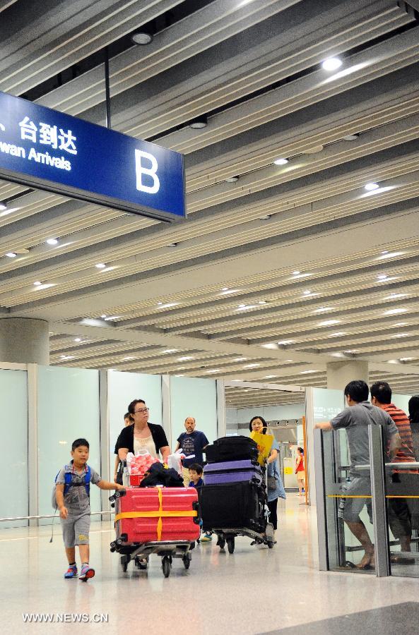 Passengers walk out of the B Exit of Terminal 3 in Beijing Capital International Airport in Beijing, capital of China, July 20, 2013. A disabled man from east China's Shandong Province set off a home-made explosive device outside the exit at around 6:24 p.m. Saturday. He suffered no life-threatening injuries and no other injuries were caused. The police cordon at the arrivals exit was removed, and the airport has resumed normal order. (Xinhua)