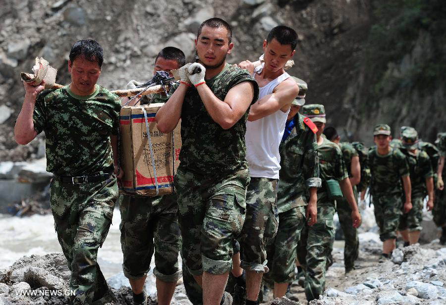 Relief workers carry disaster-relief supplies on the restored road in Caopo Township of Wenchuan County, southwest China's Sichuan Province, July 20, 2013. The road lingking Caopo Township and outside which was badly damaged by previous mud-rock flow has been reopened on Saturday, which will facilitate future rescue work in the town.(Xinhua/He Haiyang) 