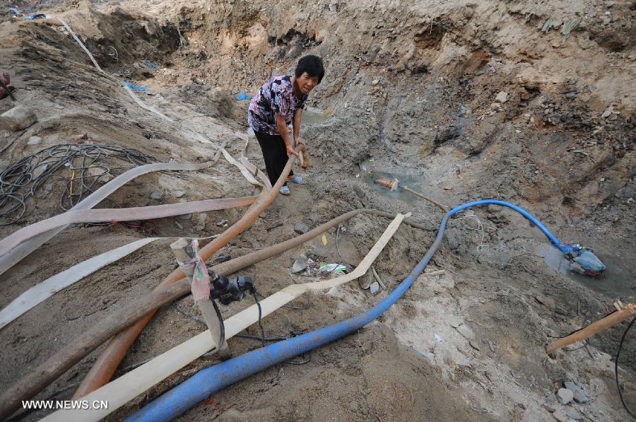 A villager pumps underground water in the Jingzi Town of Shuangfeng County, central China's Hunan Province, July 20, 2013. The drought has left about 283,000 people short of water in Hunan following days of heat, affecting 3.376 million mu (about 225,066 hectares) of croplands. (Xinhua/Nai Jihui)  
