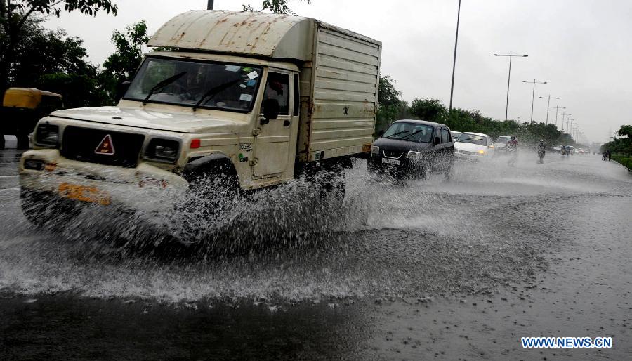 Vehicles move through the water-logged road in New Delhi, India, July 20, 2013. Heavy rainfall lashed the national capital Saturday, causing water-logging and affecting traffic. (Xinhua/Partha Sarkar) 