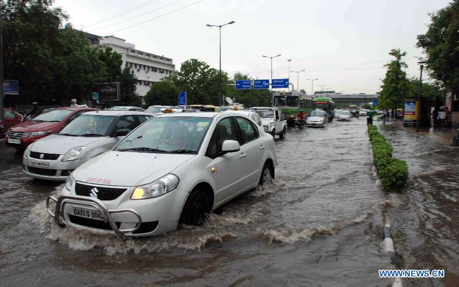 Vehicles move through the water-logged road in New Delhi, India, July 20, 2013. Heavy rainfall lashed the national capital Saturday, causing water-logging and affecting traffic. (Xinhua/Partha Sarkar)