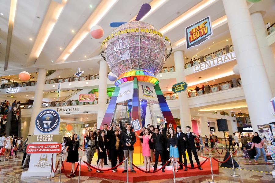 A member of a shopping mall's management staff holds the certificate of a Guinness World Record for the world's largest capsule vending machine, during a sales promotion event at a shopping mall in Kuala Lumpur, capital of Malaysia, on July 20, 2013. The machine which can contain 125,000 capsules will be used here for four months. (Xinhua/Chong Voon Chung) 