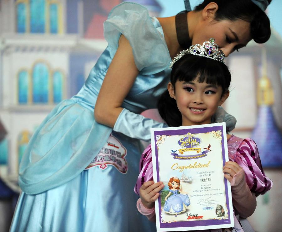 Actress Annie Lau looks after the attire of a little girl who wins a certificate of achievement in the final of "Sofia the First" Little Princess Recruitment in south China's Hong Kong, July 21, 2013. "Sofia the First" is a television cartoon series produced by Disney. In total 25 little girls competed during the final recruitment organized by Disney Junior channel. (Xinhua/Zhao Yusi)