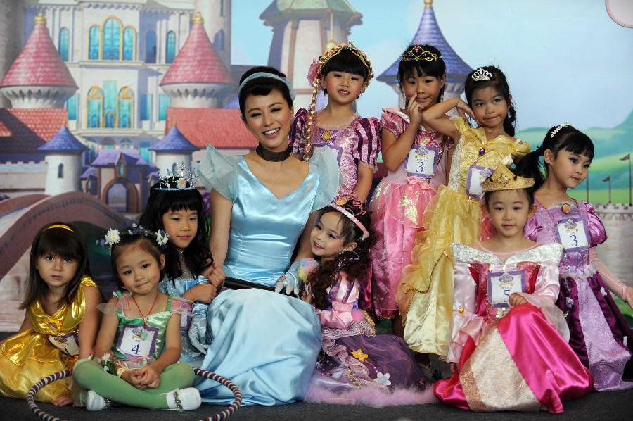 Actress Annie Lau (C) poses for a group picture with little girls participating in the final of "Sofia the First" Little Princess Recruitment in south China's Hong Kong, July 21, 2013. "Sofia the First" is a television cartoon series produced by Disney. In total 25 little girls competed during the final recruitment organized by Disney Junior channel. (Xinhua/Zhao Yusi)