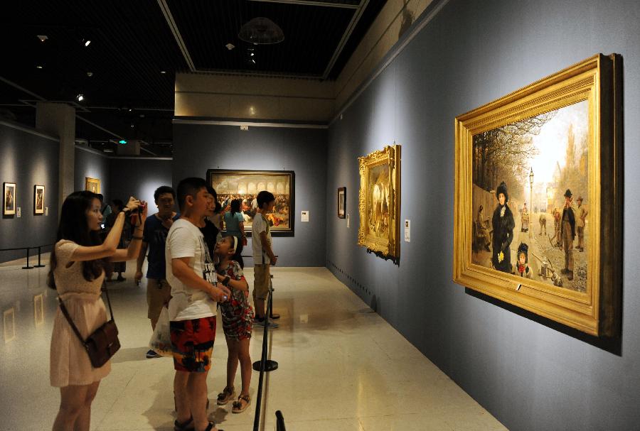 People look at paintings at an exhibition displaying works of art from public collection in northwest England in Zhengzhou, capital of central China's Henan Province, July 21, 2013. Many local citizens spent their weekends by visiting the exhibition, which lasts from June 25, 2013 to Aug. 9, 2013 at Henan Museum. (Xinhua/Li Bo)