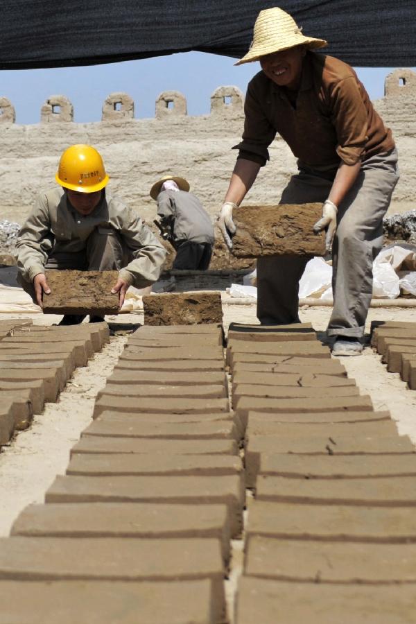Workers pack bricks prepared for the maintenance of walls of the Jiayu Pass, the starting point of a section of the Great Wall constructed during the Ming Dynasty (1368-1644) in Jiayuguan City, northwest China's Gansu Province, July 21, 2013. Built in 1372, the Jiayu Pass also served as a vital passage on the ancient Silk Road. It was listed on UNESCO's World Heritage List in 1987. China has poured 2.03 billion yuan (about 328 million US dollars) in maintaining the Jiayu Pass, also including the construction of a world culture heritage inspection center and a heritage protection and display project at the end of 2011. The local cultural relics bureau announced Sunday that the maintenance project, the largest one since the Pass was set up, has entered the critical stage. (Xinhua/Chen Bin) 