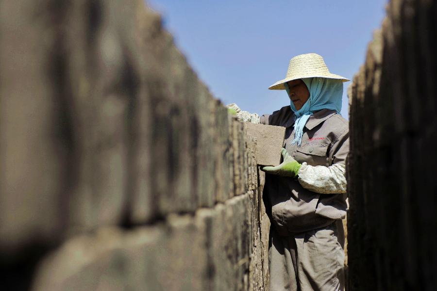 A worker packs bricks prepared for the maintenance of walls of the Jiayu Pass, the starting point of a section of the Great Wall constructed during the Ming Dynasty (1368-1644) in Jiayuguan City, northwest China's Gansu Province, July 21, 2013. Built in 1372, the Jiayu Pass also served as a vital passage on the ancient Silk Road. It was listed on UNESCO's World Heritage List in 1987. China has poured 2.03 billion yuan (about 328 million US dollars) in maintaining the Jiayu Pass, also including the construction of a world culture heritage inspection center and a heritage protection and display project at the end of 2011. The local cultural relics bureau announced Sunday that the maintenance project, the largest one since the Pass was set up, has entered the critical stage. (Xinhua/Chen Bin) 