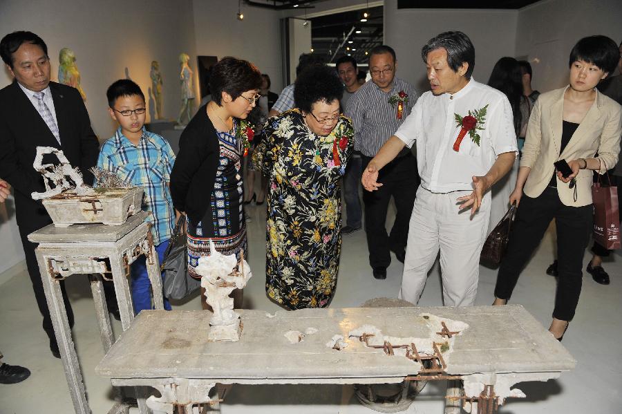 Honored guests and visitors look at an exhibition of the awarded sculpture works of 2013 college graduates in Beijing, capital of China, July 21, 2013. These awarded works are presented to the public from July 21, 2013 to July 25, 2013 here. (Xinhua/Lu Peng)