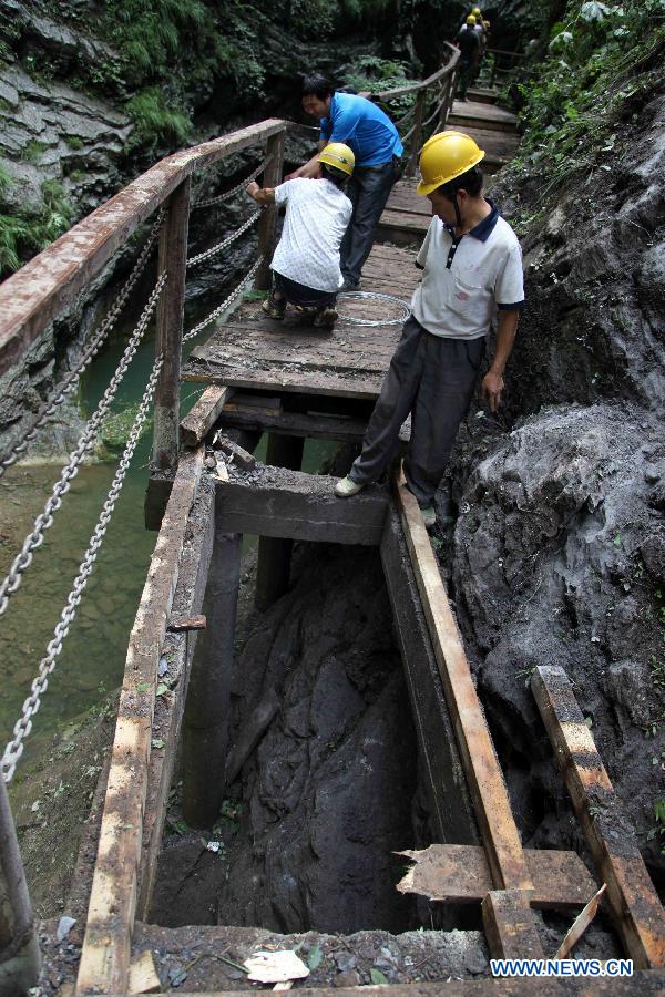 Workers repair a rim skywalk after a landslide in the Jinsixia Gorge, northwest China's Shaanxi Province, July 21, 2013. One tourist was killed and 18 others injured by falling rocks at Jinsixia Gorge on Sunday morning. The gorge has been closed temporarily. (Xinhua)