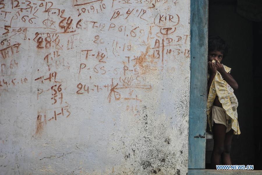 A little girl stands next to the door of her house in the village of Gandaman, Saran District of eastern Indian state of Bihar, July 21, 2013. At least 23 children, all below 12 years, were confirmed dead due to food poisoning after eating a free mid-day school meal in the eastern Indian state of Bihar on July 16, 2013. (Xinhua/Zheng Huansong) 