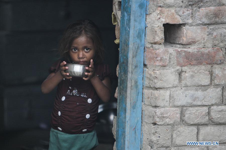 A little girl, whose elderly sister was killed in a mass food poisoning, stands next to the door of her house in the village of Gandaman, Saran District of eastern Indian state of Bihar, July 21, 2013. At least 23 children, all below 12 years, were confirmed dead due to food poisoning after eating a free mid-day school meal in the eastern Indian state of Bihar on July 16, 2013. (Xinhua/Zheng Huansong) 