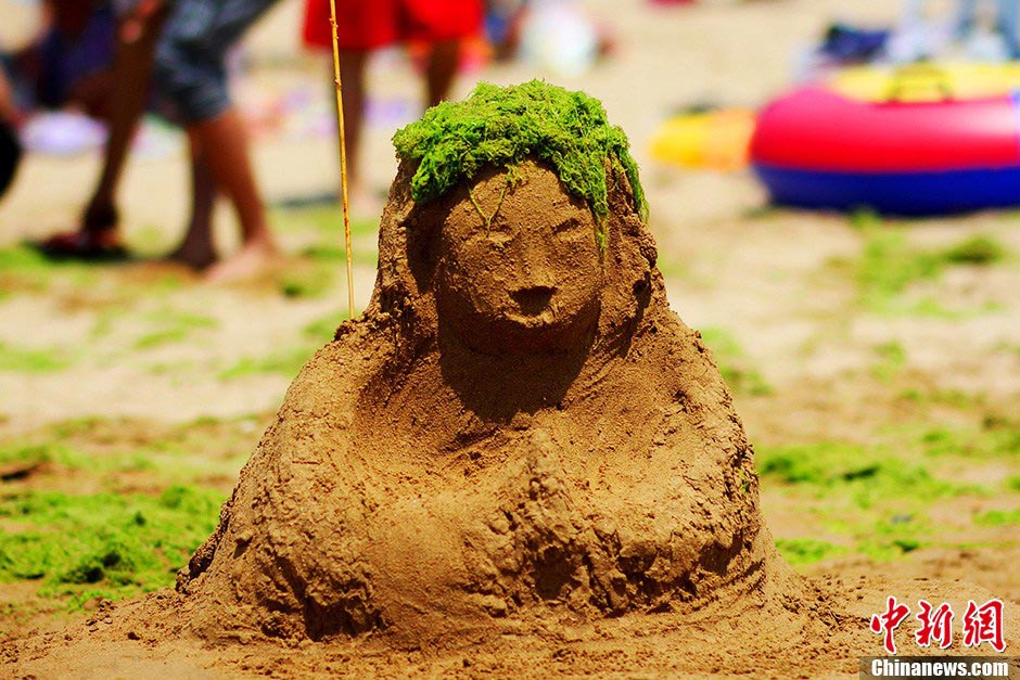 A lovely sand sculpture "portrait" appears on the Old Stone Man Beach (Shi Laoren Beach) in Qingdao, east China's Shandong province, causing attention from tourists, July 18, 2013. Interestingly, the portrait's hair is decorated with green algae, making it vivid and funny. (CNS/Xue Hun)