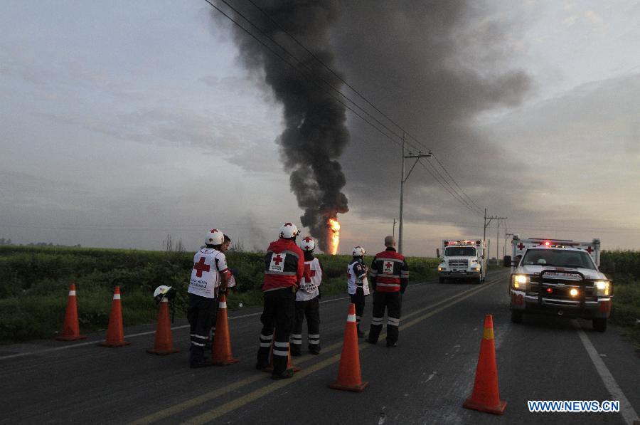 Elements of the Red Cross, firemen and policemen work near the place where a fire was registered in a duct of the Mexican oil company Pemex, in the Tonanitla municipality, in the State of Mexico, Mexico, on July 21, 2013. The oil spill and fire in Tonanitla were caused by a clandestine outlet to extract the fuel, Pemex confirmed in a statement. Until now, the authorities have reported 6 people wounded, two of them belonging to the fire brigade and four municipal policemen. (Xinhua/Juan Carlos Villa)