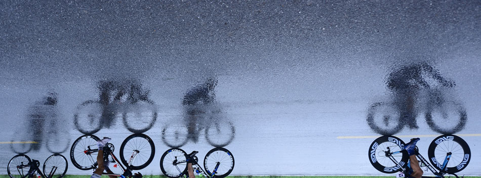 The shadow of racers is reflected on the wet pavement, on July 14, 2013. The 12th session of the Qinghai Lake International Road Cycling Race opened in Qinghai. (Xinhua/Zhang Hongxiang)