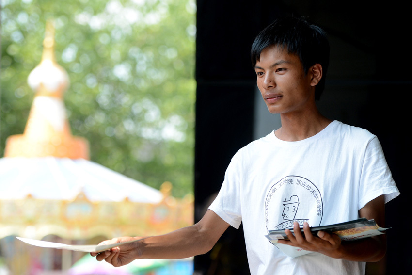 Xiong Wenjun distributes leaflets to pedestrians on July 19.  (Xinhua/ Zhang Rui) 