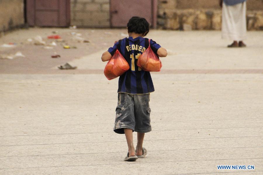 A boy walks back home with free food from a charity organization In Sanaa, Yemen, July 22, 2013. The United Nations humanitarian envoy in Yemen appealed to the international community to provide 702 million U.S. dollars in aid of some seven million people affected by conflict and instability in Yemen. (Xinhua/Mohammed Mohammed) 