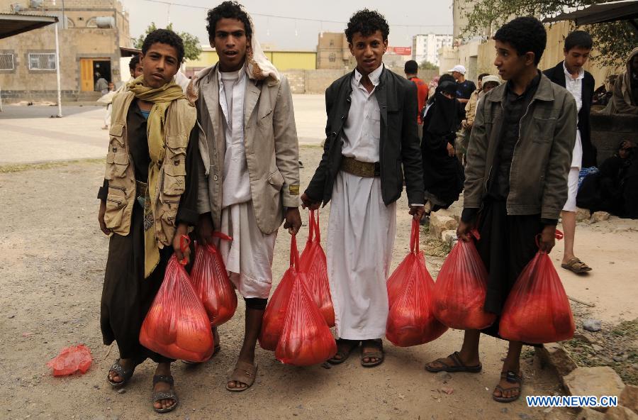 People with free food from a charity organization pose for a photo in Sanaa, Yemen, July 22, 2013. The United Nations humanitarian envoy in Yemen appealed to the international community to provide 702 million U.S. dollars in aid of some seven million people affected by conflict and instability in Yemen. (Xinhua/Mohammed Mohammed) 