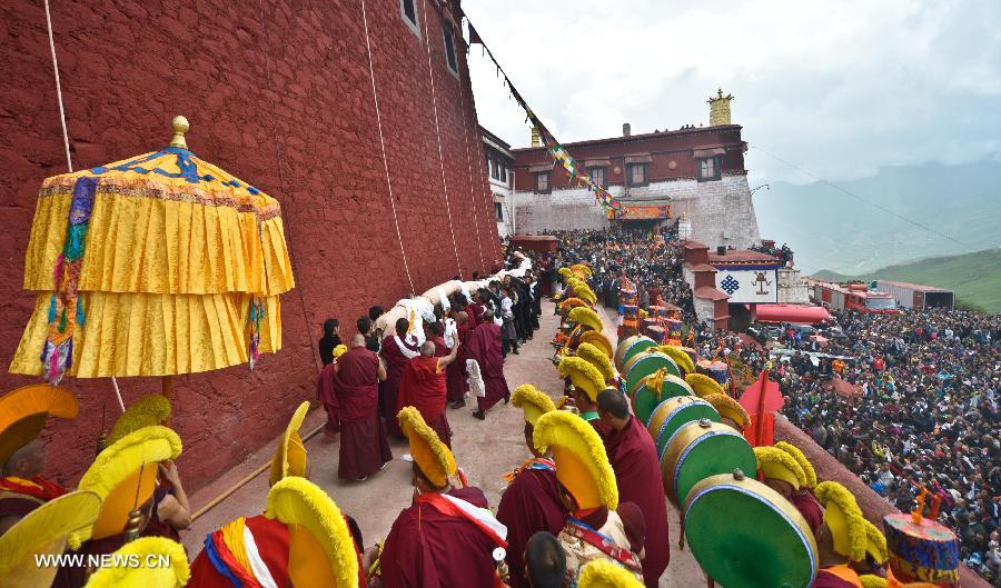 Monks carry a roll of a huge Buddha portrait before unfolding it during the annual religious ritual in the Gandan Temple in Lhasa, capital of southwest China's Tibet Autonomous Region, July 22, 2013. Founded in 1409 by followers of Zong Kaba, founder of the Yellow Sect of Tibetan Buddhism, the Gandan Temple is the oldest among lamaseries of the Yellow Sect. (Xinhua/Purbu Zhaxi)