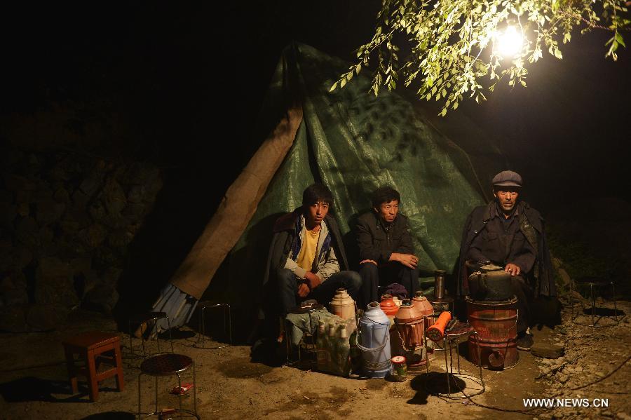 Residents sit beside a tent at Chagu Village of Meichuan Town in Minxian County, northwest China's Gansu Province, early July 23, 2013. The death toll has climbed to 89 in the 6.6-magnitude earthquake which jolted a juncture region of Minxian County and Zhangxian County in Dingxi City Monday morning. (Xinhua/Liu Xiao)