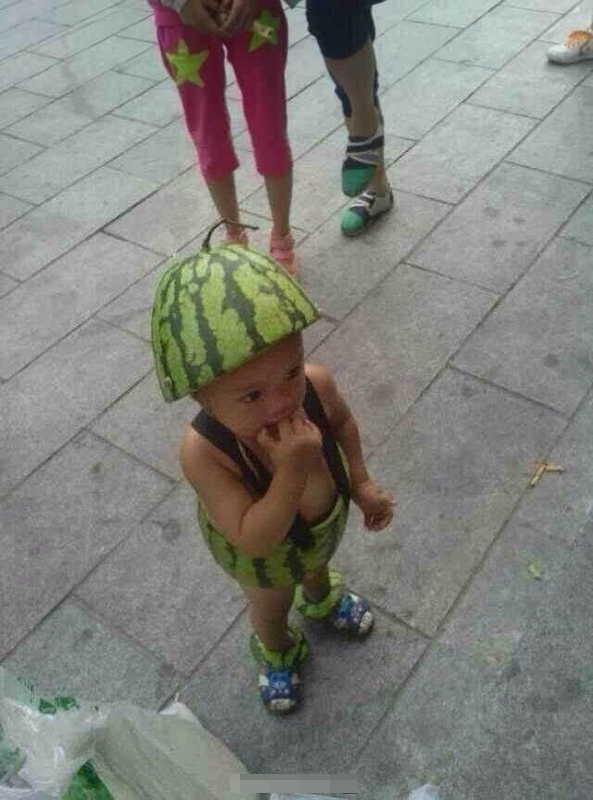 A kid beats summer heat by covering the body with the skin of half a watermelon in Wenzhou, east China's Zhejiang province. (Photo/ people.com.cn)