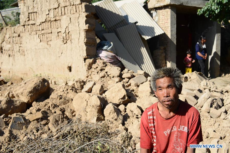 Villager Zhu Ga sits in front of his house after a quake in Majiagou Village, Meichuan Town, Minxian County, northwest China's Gansu Province, July 22, 2013. A 6.6-magnitude quake jolted the border of Minxian and Zhangxian counties in Gansu at 7:45 a.m. on Monday. (Xinhua/Jin Liangkuai)