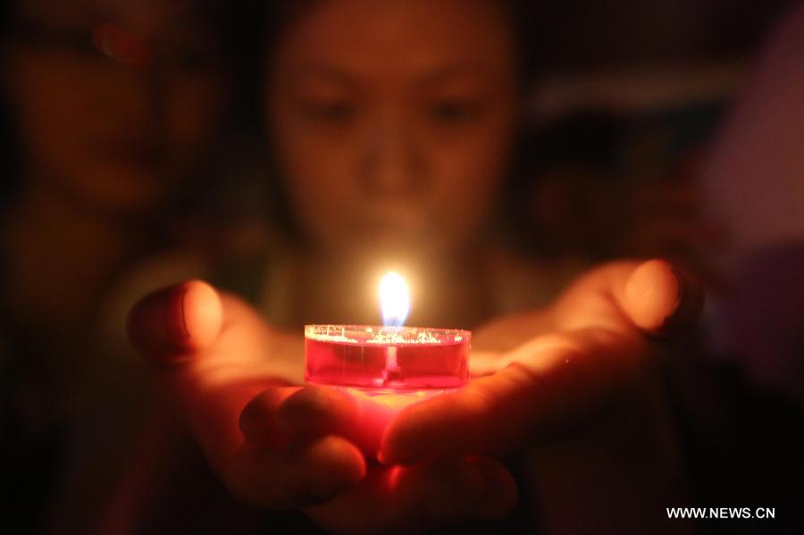 A volunteer holds candles as they pray for the residents and victims of quake-hit Dingxi City in northwest China's Gansu Province, in Loudi City, central China's Hunan Province, July 22, 2013. A 6.6-magnitude earthquake jolted a juncture region of Minxian County and Zhangxian County in Dingxi City Monday morning, leaving 89 people dead. (Xinhua/Guo Guoquan)