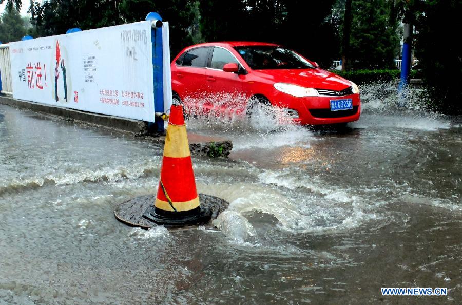 A vehicle moves on the waterlogged Minghu North Road in Jinan, capital of east China's Shandong Province, July 23, 2013. A heavy rainfall hit Jinan on Tuesday. (Xinhua/Xu Suhui)