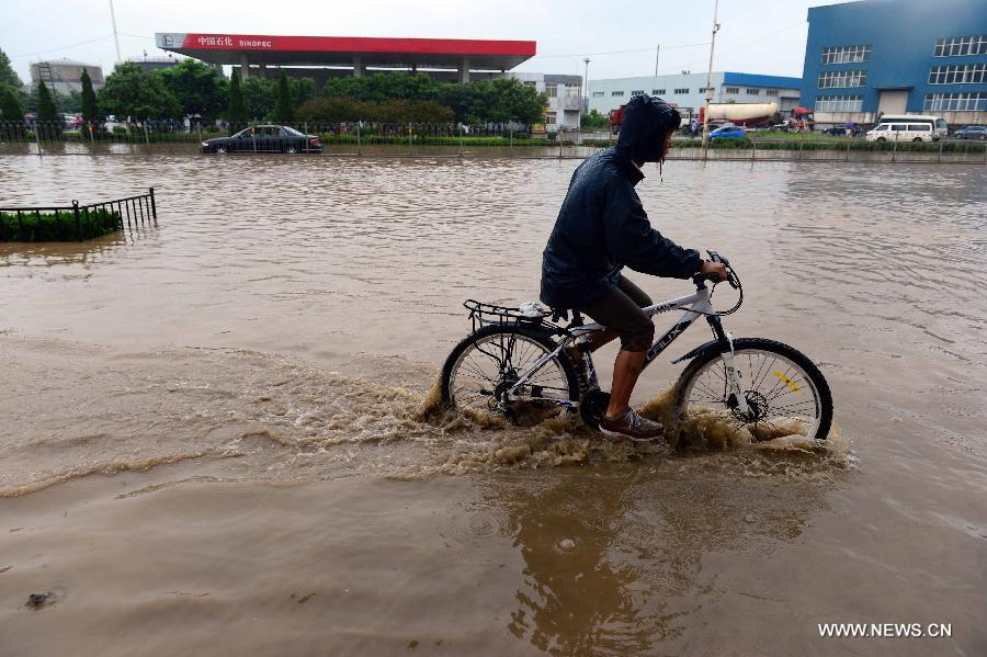 A man rides on the waterlogged Lianhua Road in Jinan, capital of east China's Shandong Province, July 23, 2013. A heavy rainfall hit Jinan on Tuesday. (Xinhua/Guo Xulei)