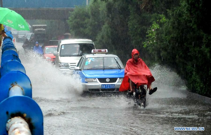 Vehicles run on the waterlogged Shengchan Road in Jinan, capital of east China's Shandong Province, July 23, 2013. A heavy rainfall hit Jinan on Tuesday. (Xinhua/Xu Suhui)