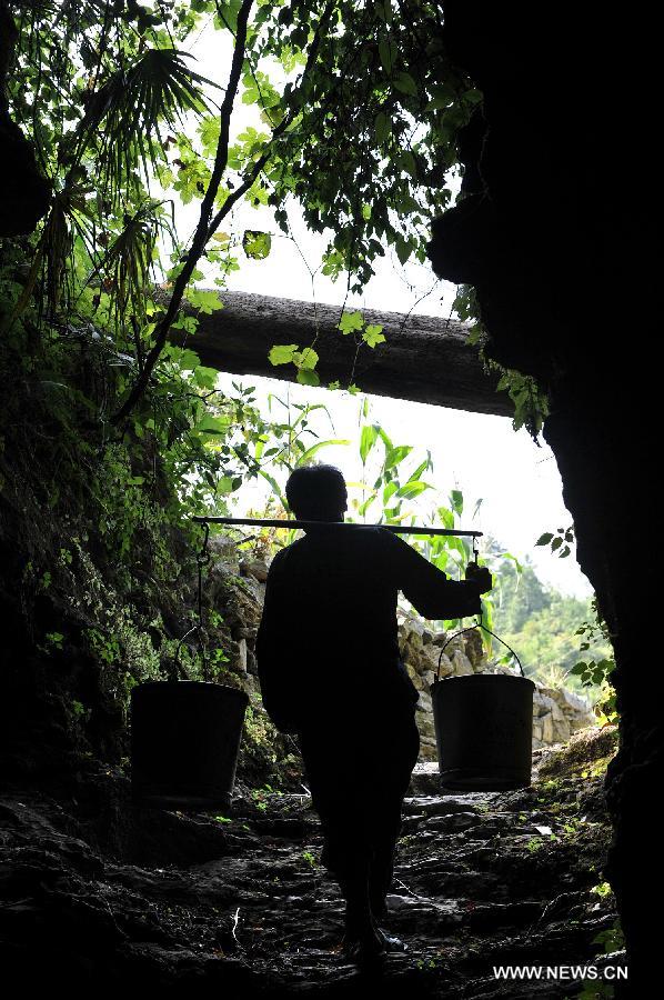 A villager fetches water from a karst cave at drought-hit Haoyou Village in Shanjiang Town of Fenghuang County, central China's Hunan Province, July 23, 2013. A drought that has lasted since early July has left 384,000 people short of drinking water in the province. Eighty-seven counties of 12 cities and prefectures in the province have been affected by the drought, with about 260,000 hectares of crops damaged and 216,000 heads of livestock short of water. Also in the province, 128 rivers and 124 reservoirs are dry. (Xinhua/Long Hongtao)
