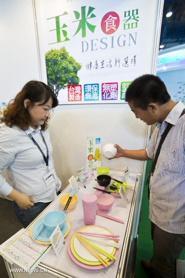A visitor views the tablewares made from corn flour at the 13th China International Environment Protection Exhibition & Conference in Beijing, capital of China, July 23, 2013. The four-day exhibition kicked off on Tuesday, attracting around 500 enterprises from more than 20 countries and regions. (Xinhua/Zhao Bing)